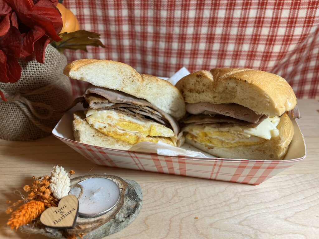 Breakfast sandwich with egg and ham in paper tray.