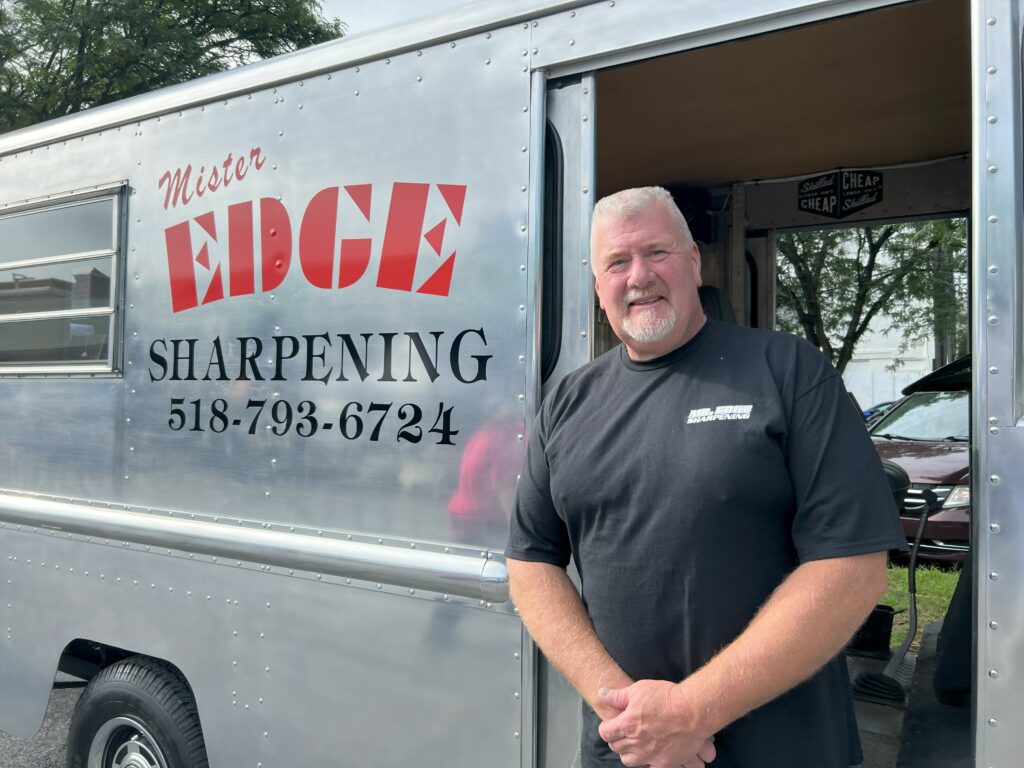 Man standing by mobile sharpening service trailer.