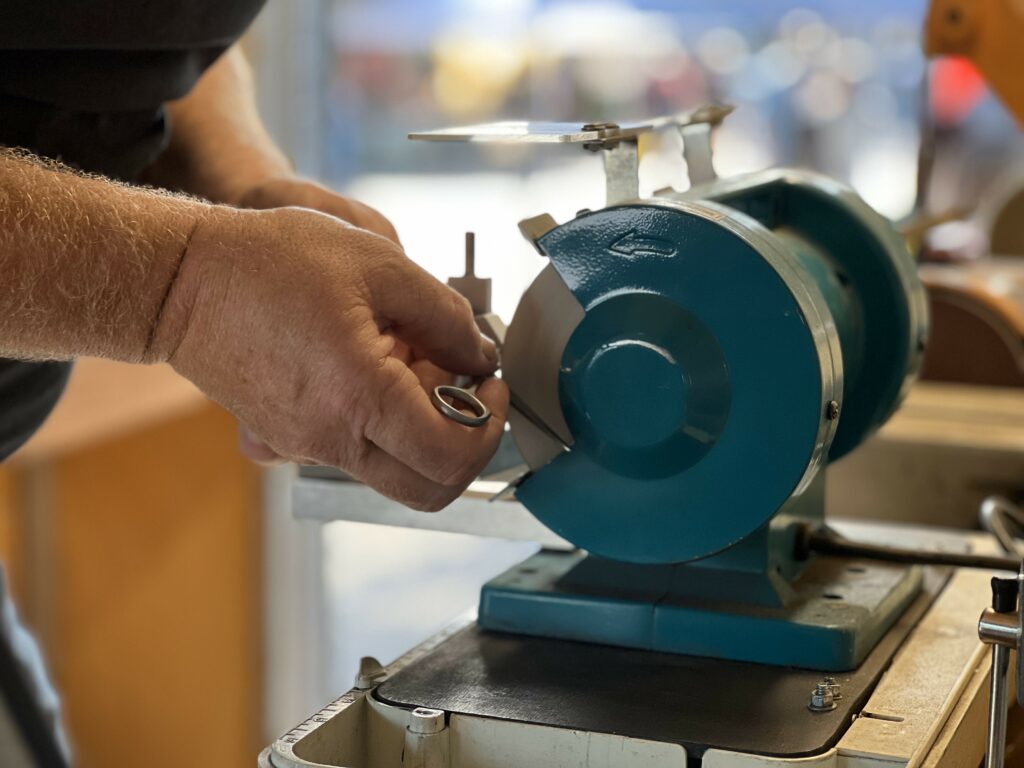 Person sharpening tool on grinding wheel.