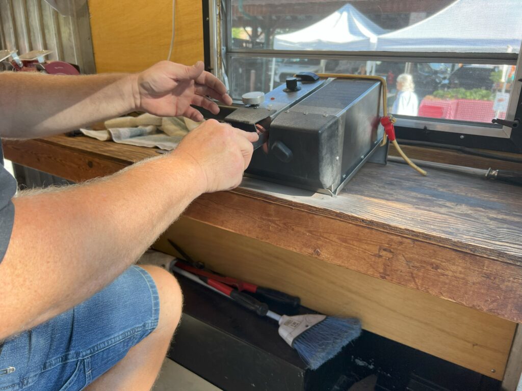 Person repairing toaster at wooden workstation.