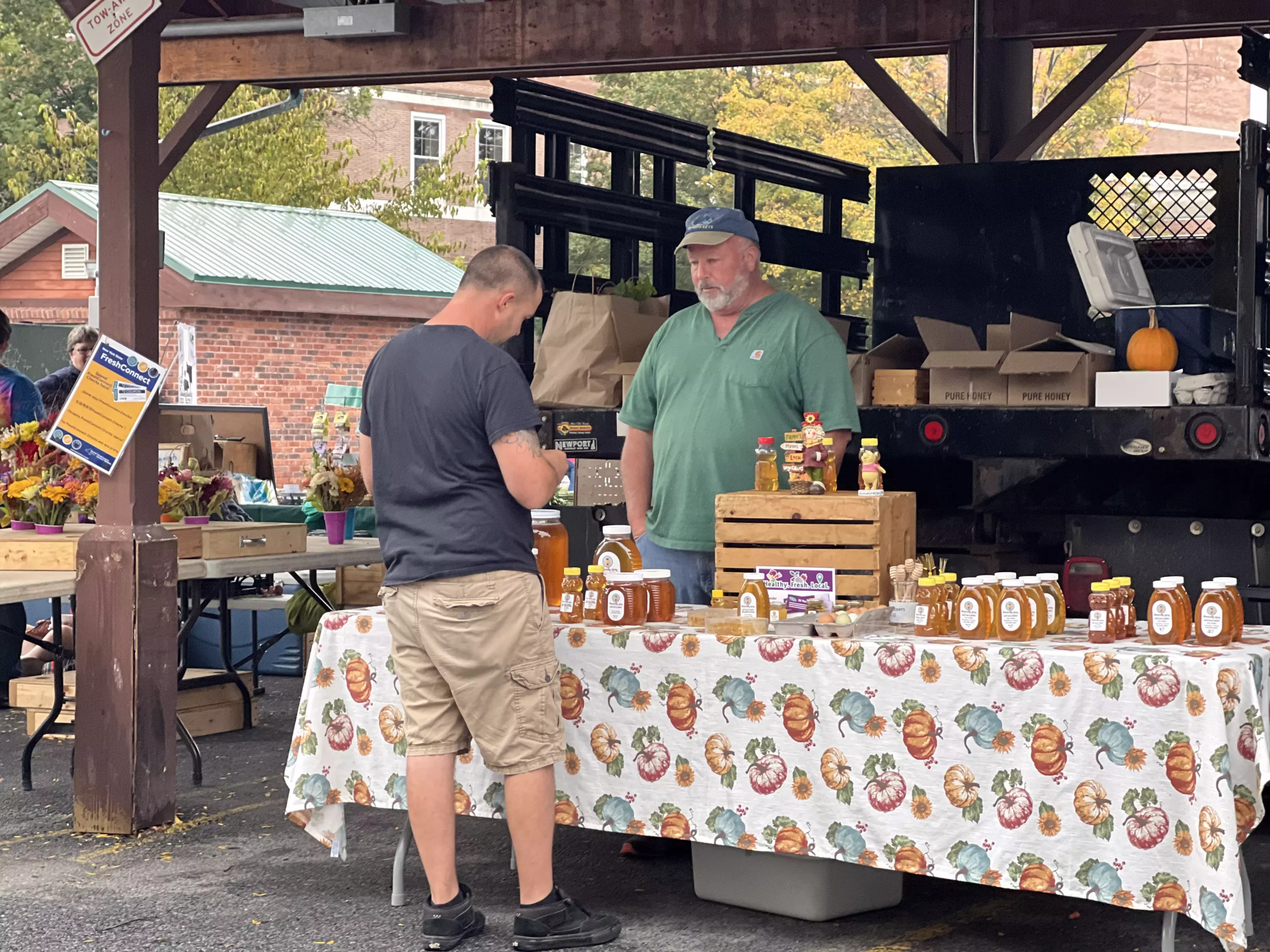 Farmers market honey stall with customers.