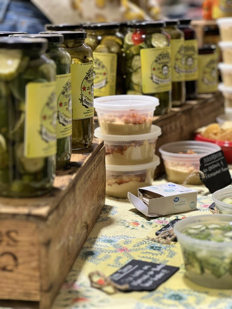 Assorted pickles in jars at market stall.