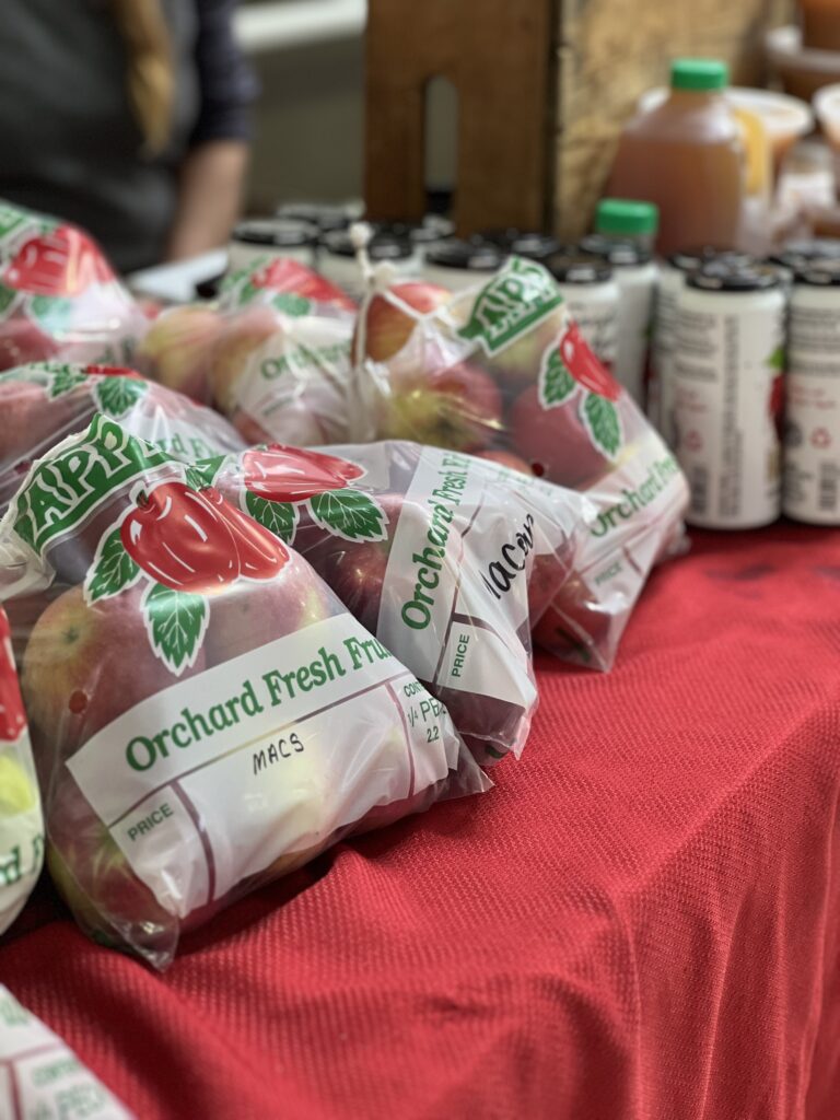 Packaged apples and beverages on market table.