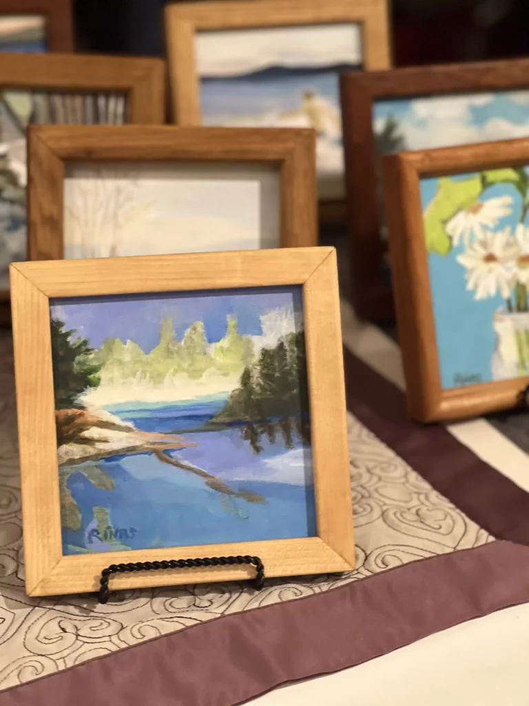 Assorted framed landscape paintings on display.