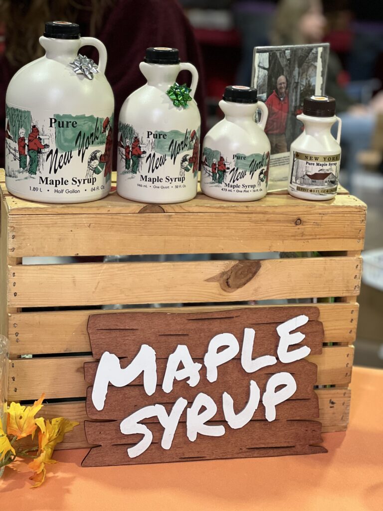 Various sizes of New York maple syrup jugs on display.