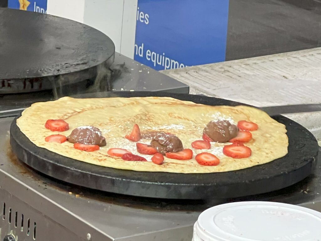 Crepes with strawberries and chocolate on hot griddle.