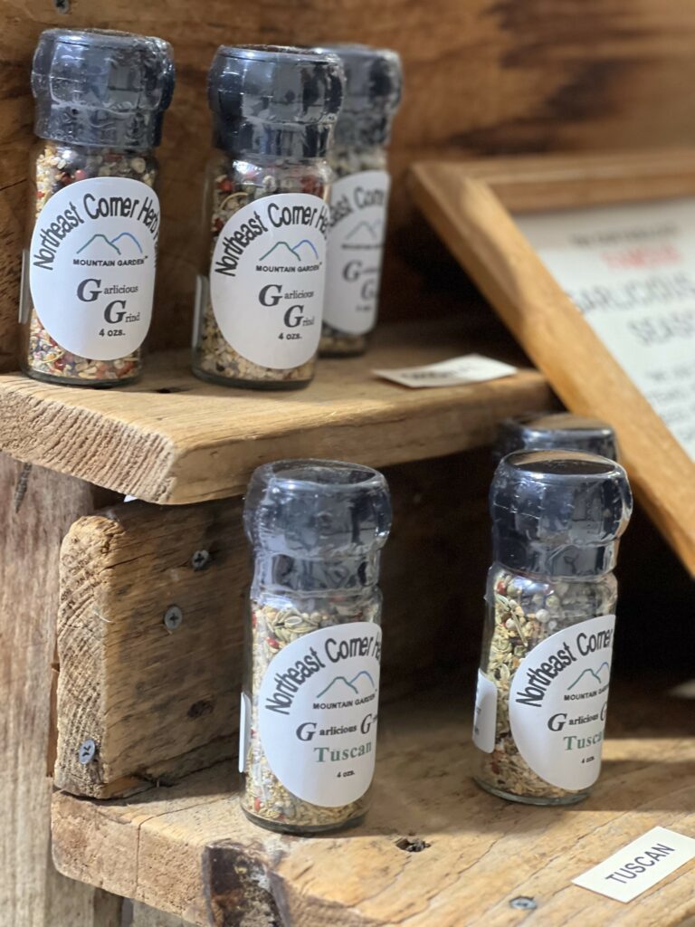 Glass jars of spices on wooden shelves.