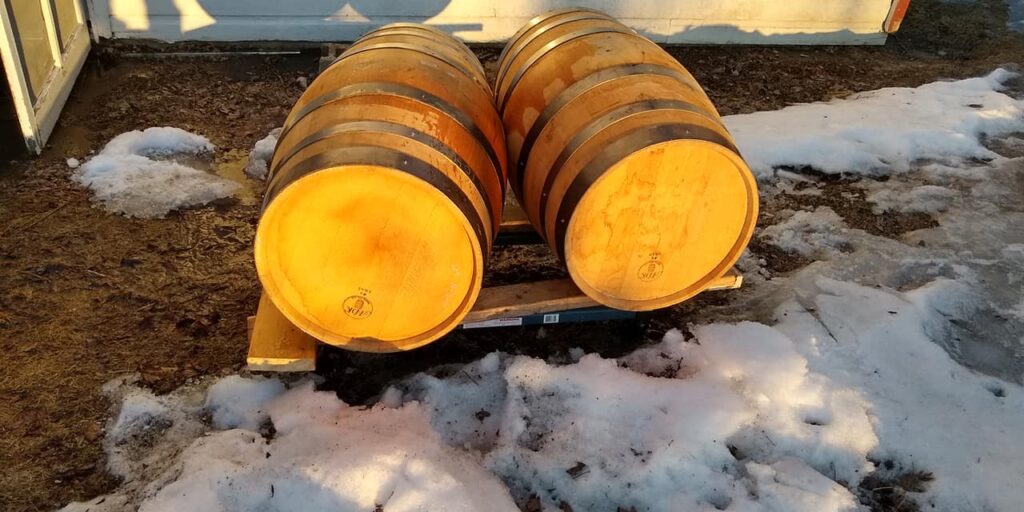 Wooden barrels on pallet in snowy outdoor setting.