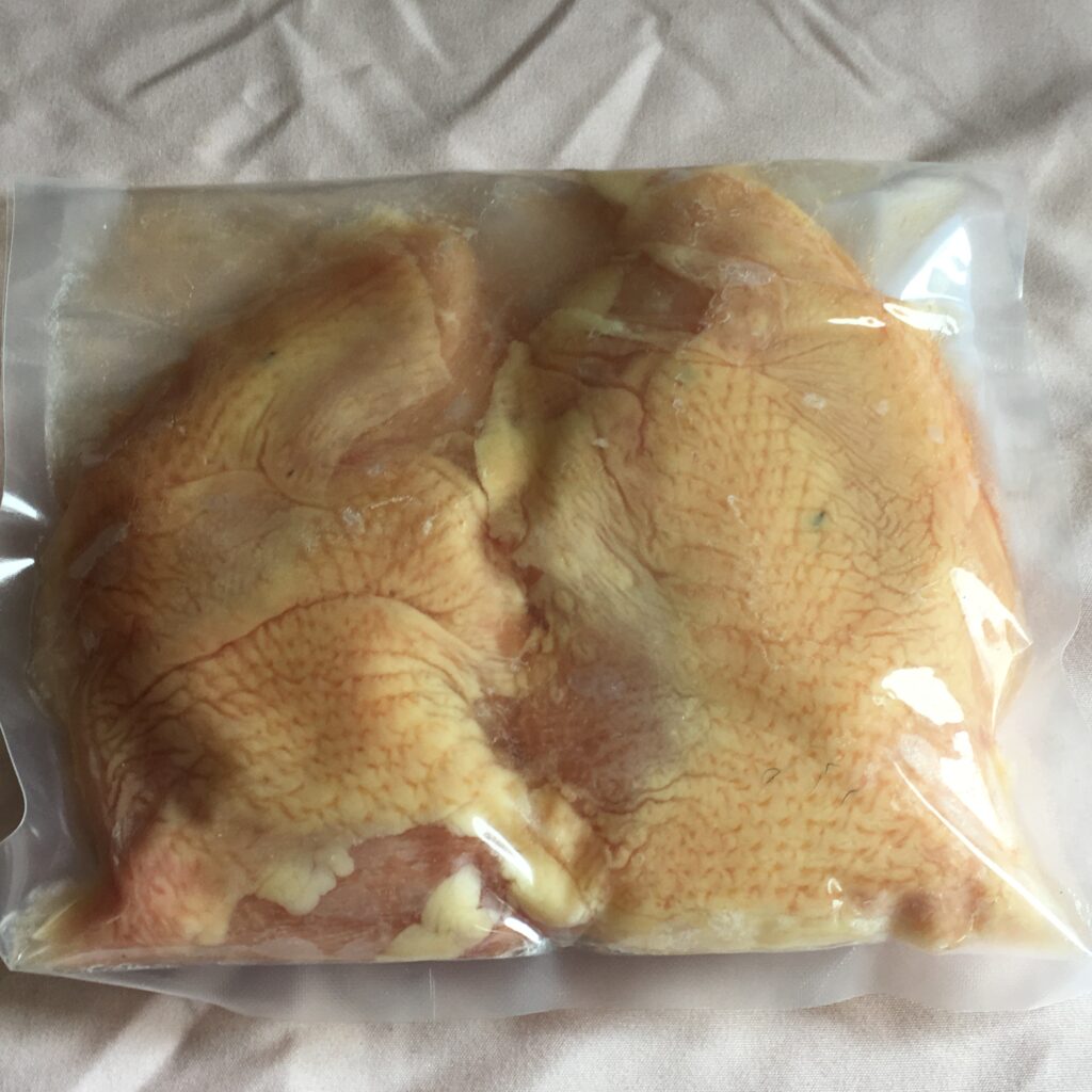 Vacuum-sealed raw chicken breasts on fabric background.