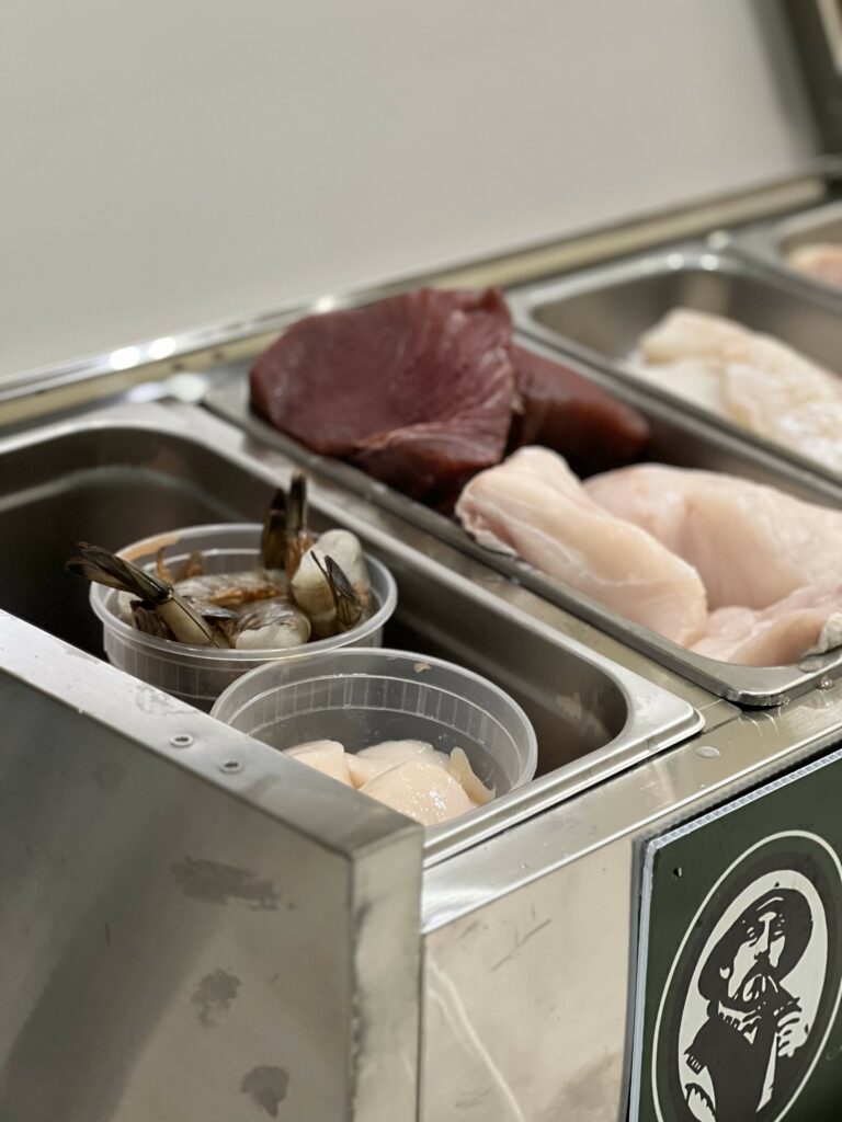 Fresh seafood selection in stainless steel trays.