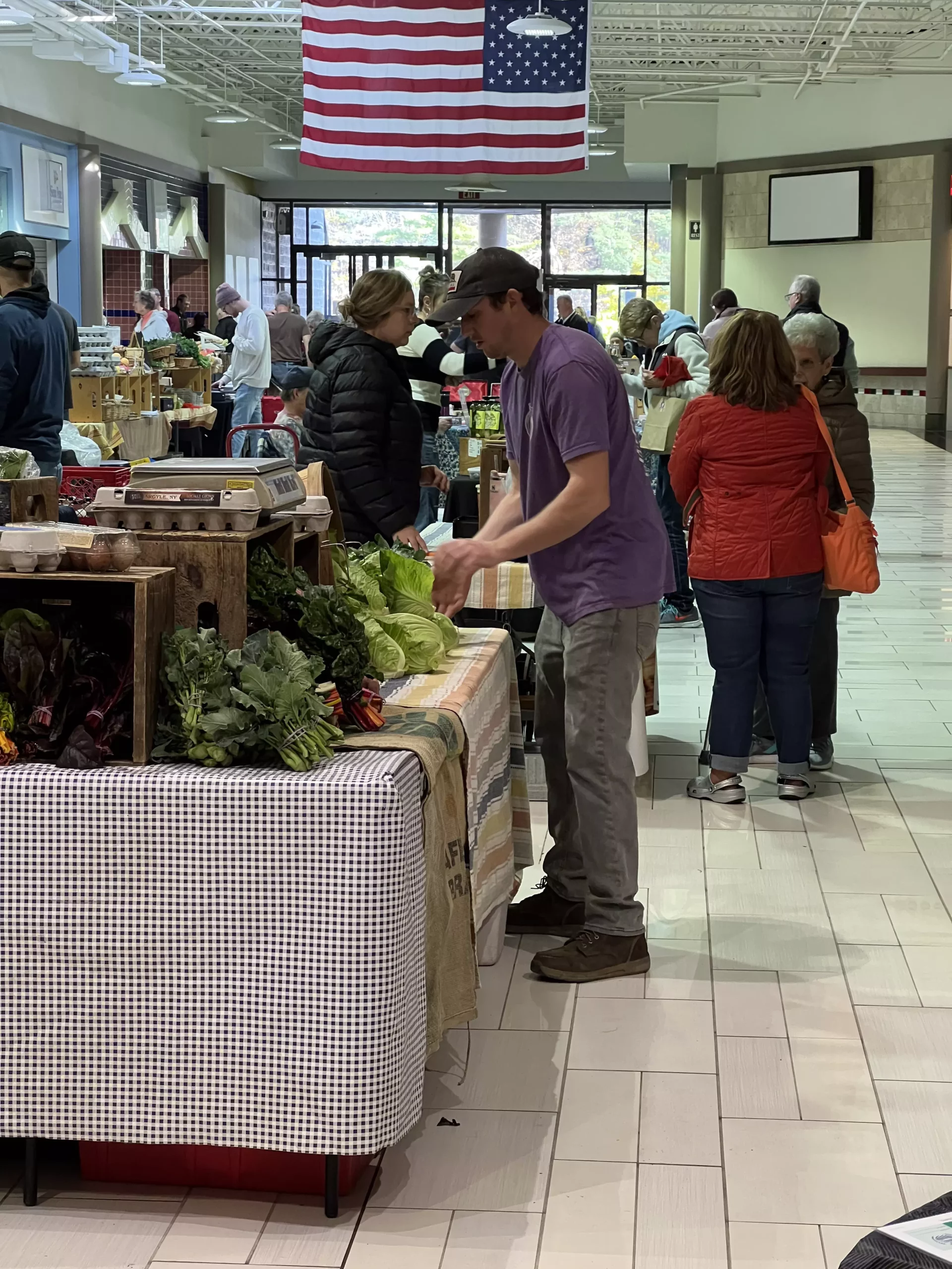 Shoppers browsing at an indoor farmers market.