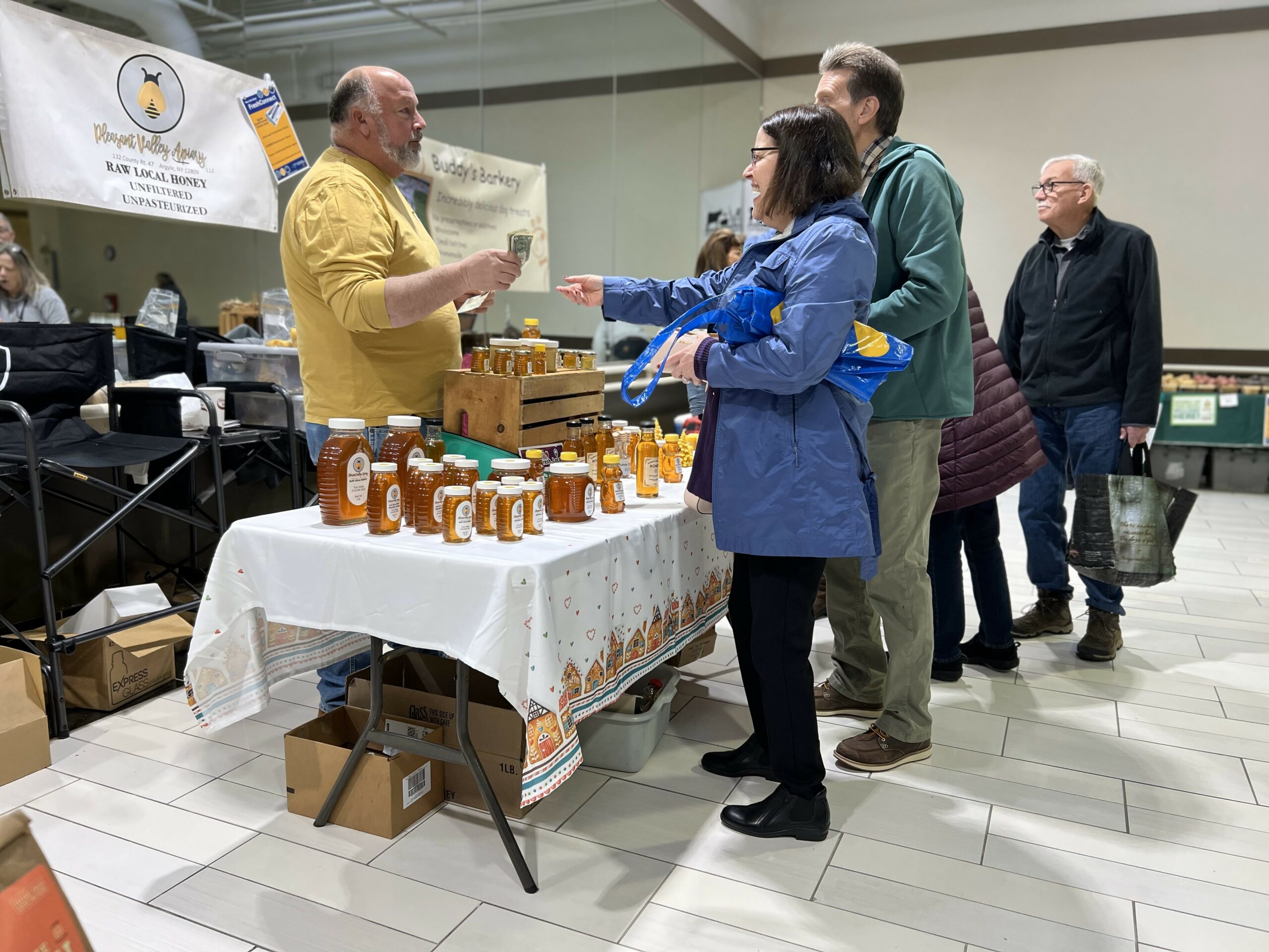 Vendor selling honey at indoor market booth.