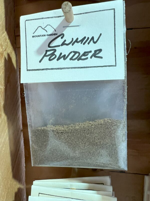 Plastic bag of cumin powder on shelf.