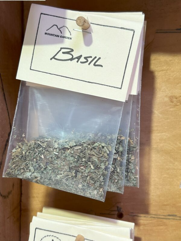 Packet of dried basil on wooden shelf.