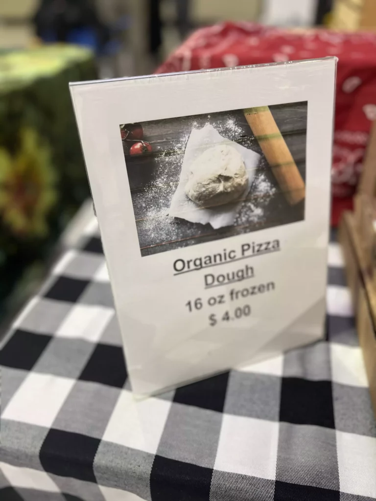 Sign displaying organic pizza dough for sale.