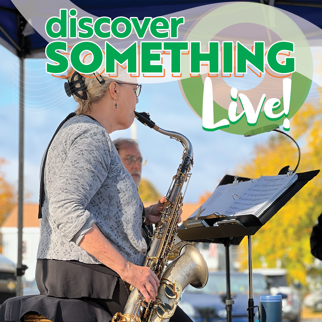 Woman playing saxophone at live outdoor event.