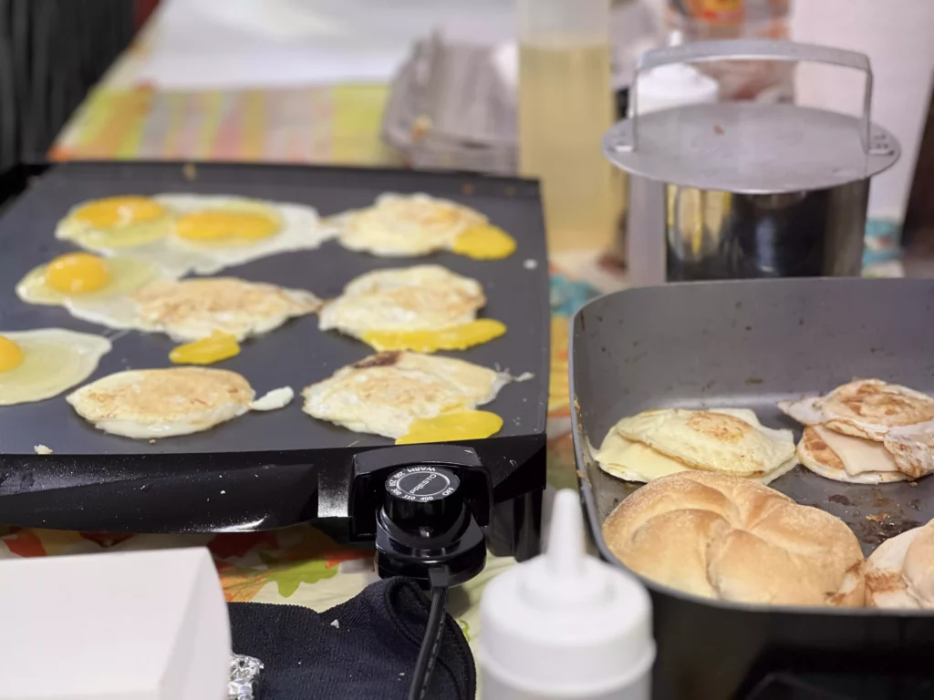 Cooking eggs and pancakes on a griddle.